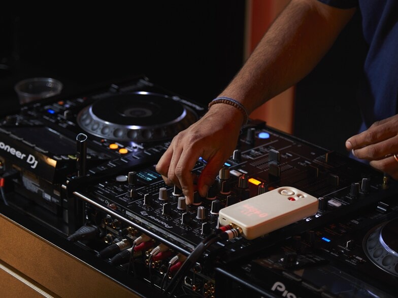 A DJ's hands on a mixer, with a Blast Box plugged into the rig.