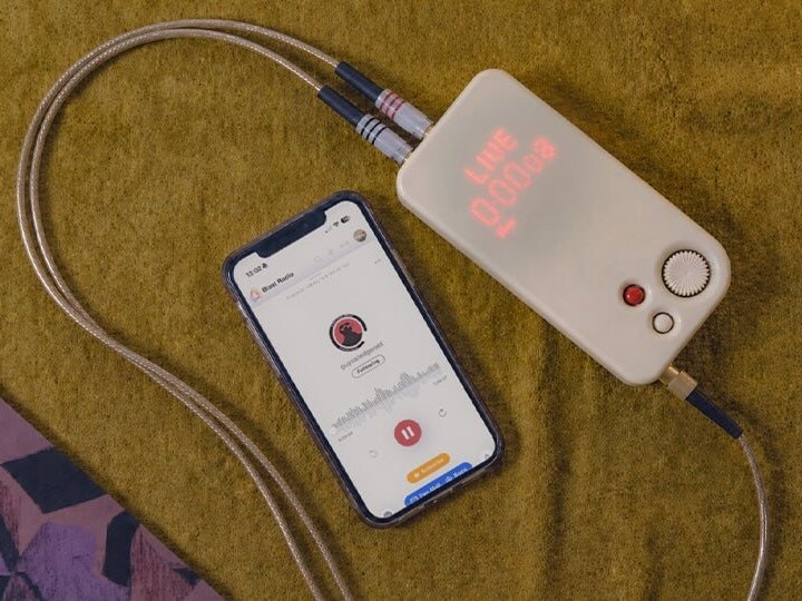 A Blast Box showing LIVE on its LED face, cabled up next to a phone running the Blast Radio app.