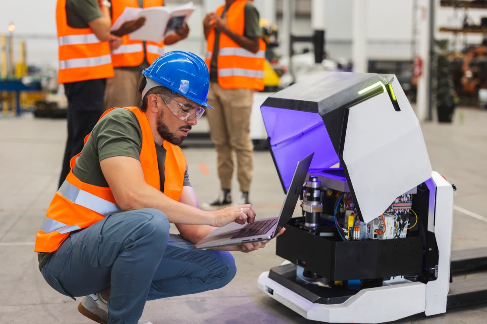 An engineer checks the electronics of an autonomous pallet robot on a warehouse floor