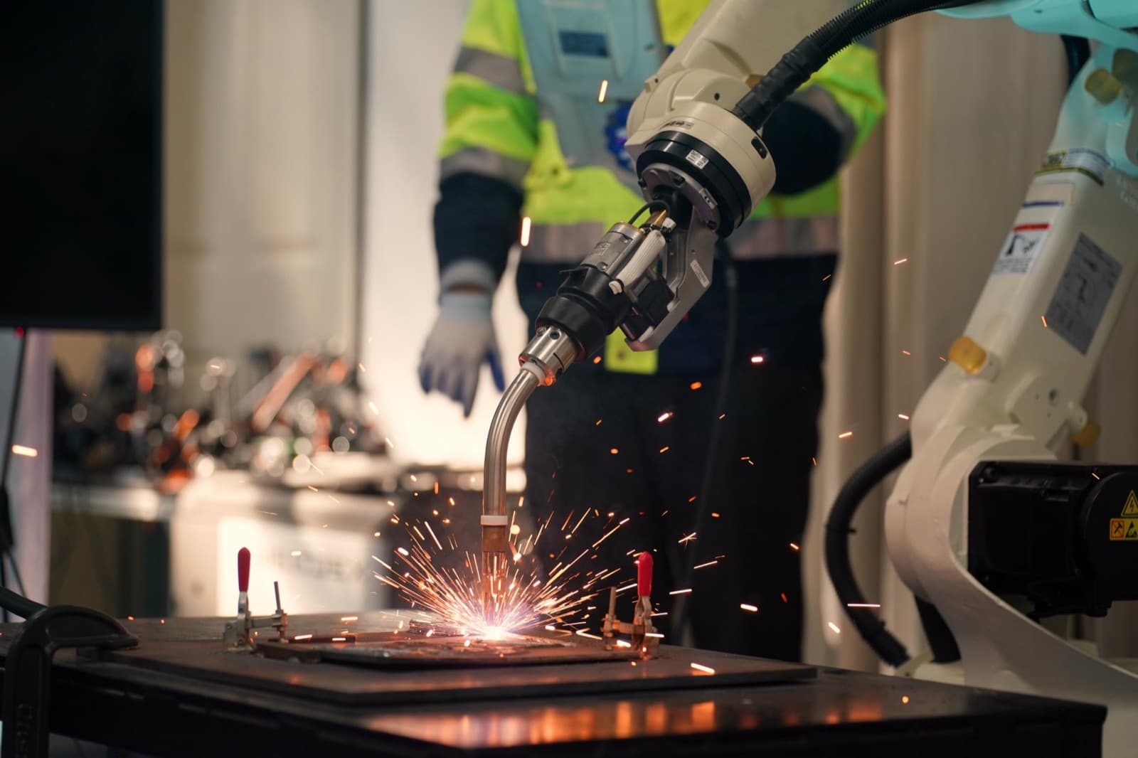 A robotic welding arm joining steel parts, sparks flying
